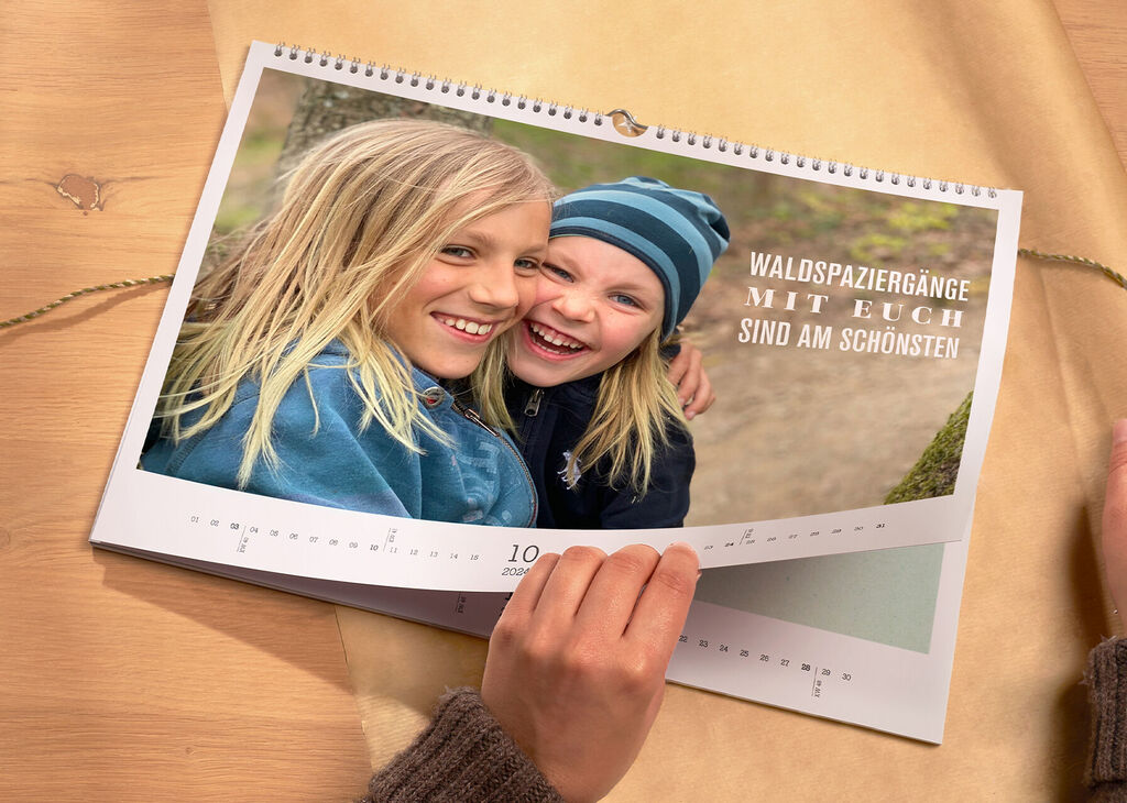 Ein geöffneter Fotokalender zeigt fröhliche Erinnerungen an einen Waldspaziergang.