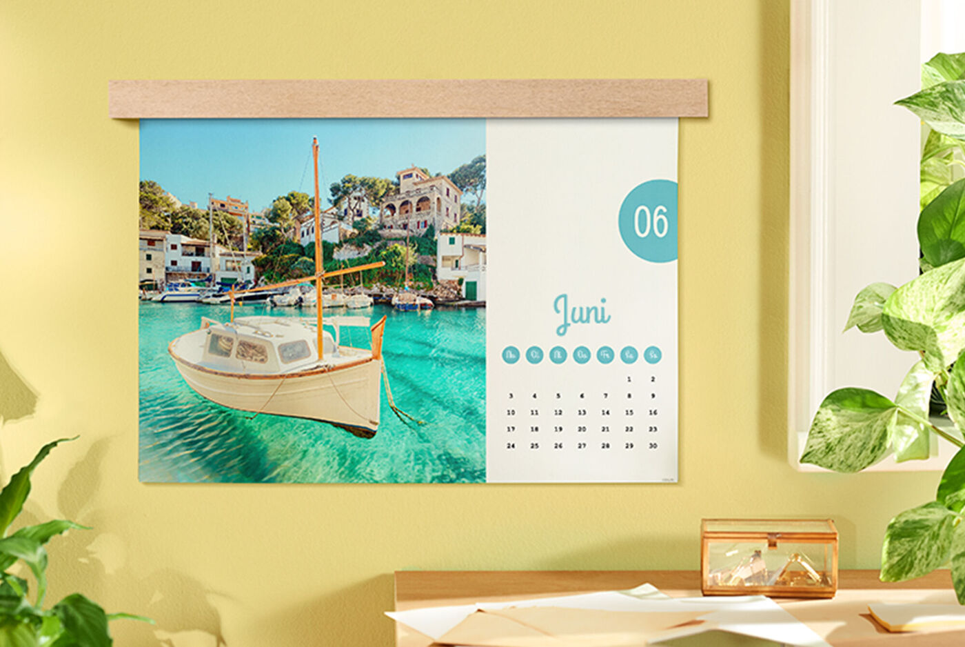 Ein CEWE Fotokalender mit einem Bild eines Bootes in klarem Wasser, umgeben von Häusern