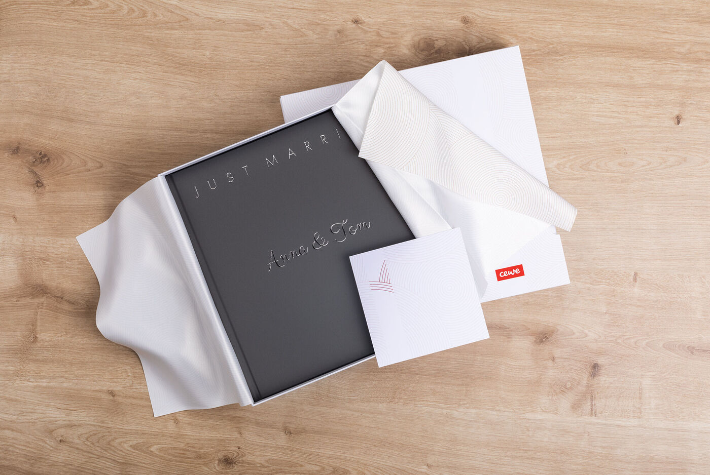 Ein romantisches CEWE FOTOBUCH mit dem Titel 'Just Married', liebevoll verpackt in einer weißen Box, bereit zum Verschenken