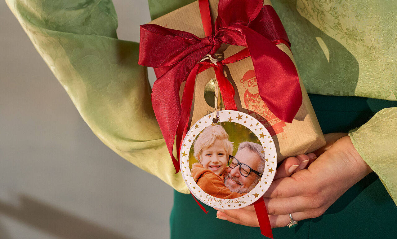 Eine Person hält ein liebevoll verpacktes Geschenk mit rotem Band.