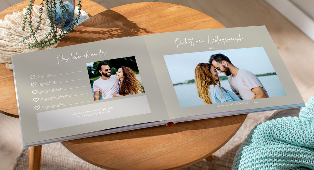 Zwei Personen lehnen sich in einem CEWE FOTOBUCH nah zueinander, umarmt und mit Lächeln, umgeben von einem schönen Rahmen.