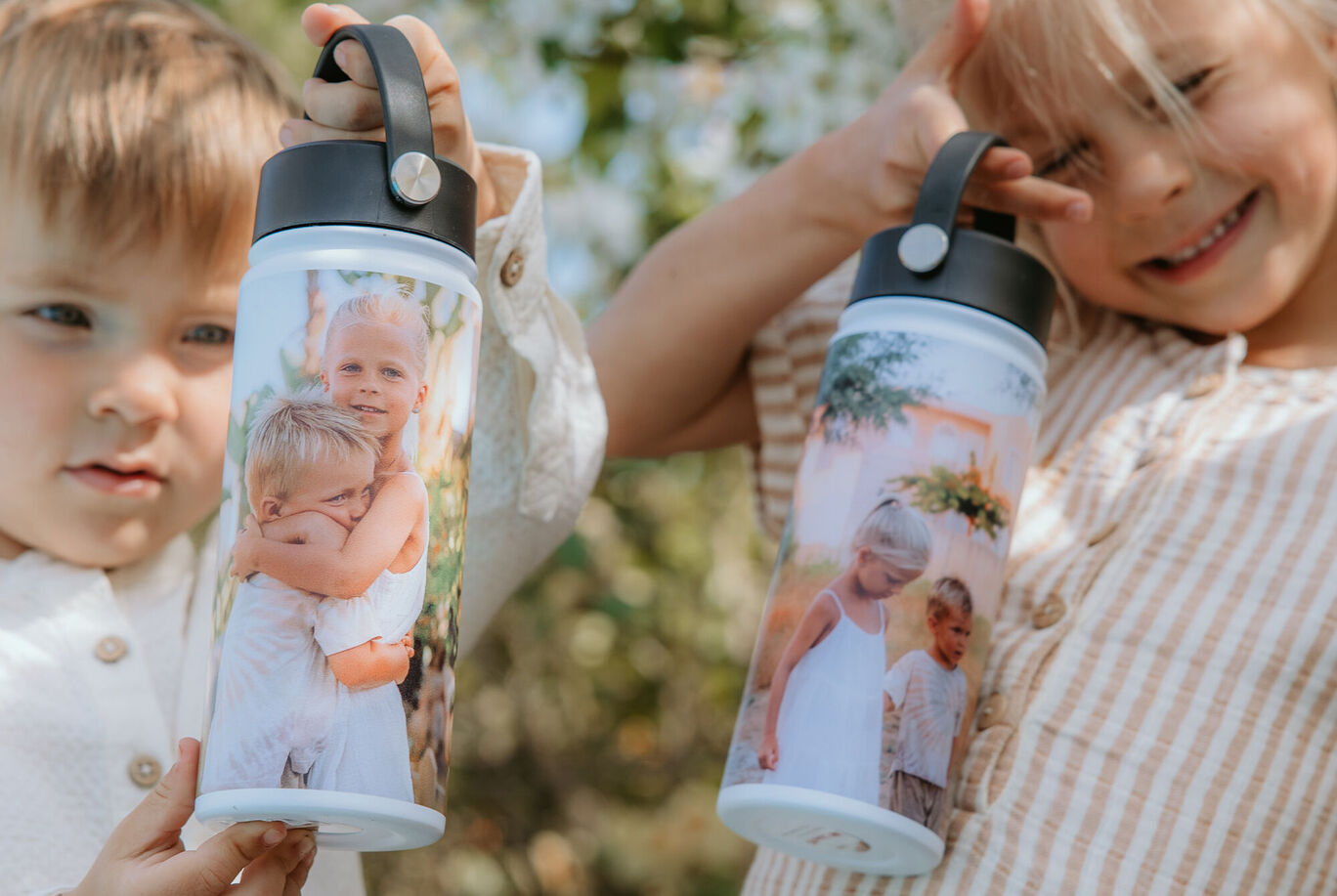 Zwei Kinder halten personalisierte Trinkflaschen mit bunten Fotos.
