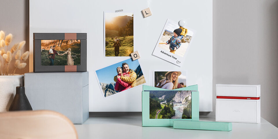 Bilderrahmen und Fotos auf einem Tisch. Schöne Erinnerungen werden präsentiert. Farbenfrohe Gestaltung wirkt einladend.
