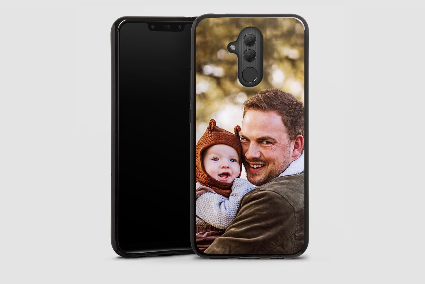 Ein Vater hält sein Kind in den Armen, mit einem Smartphone im Hintergrund