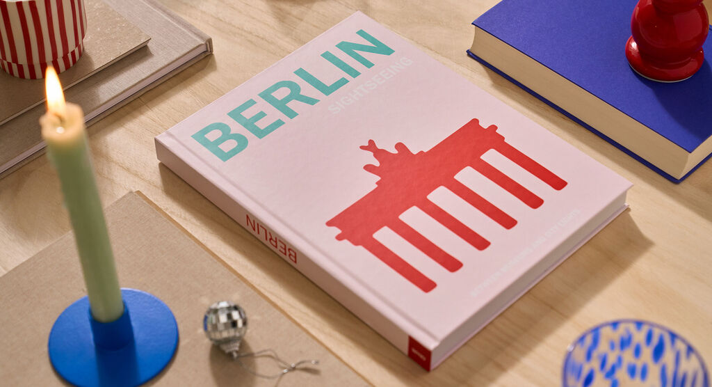Auf einem Tisch liegt ein CEWE FOTOBUCH. Das Cover ist rosa und mit dem Schriftzug „Berlin“ gestaltet.
