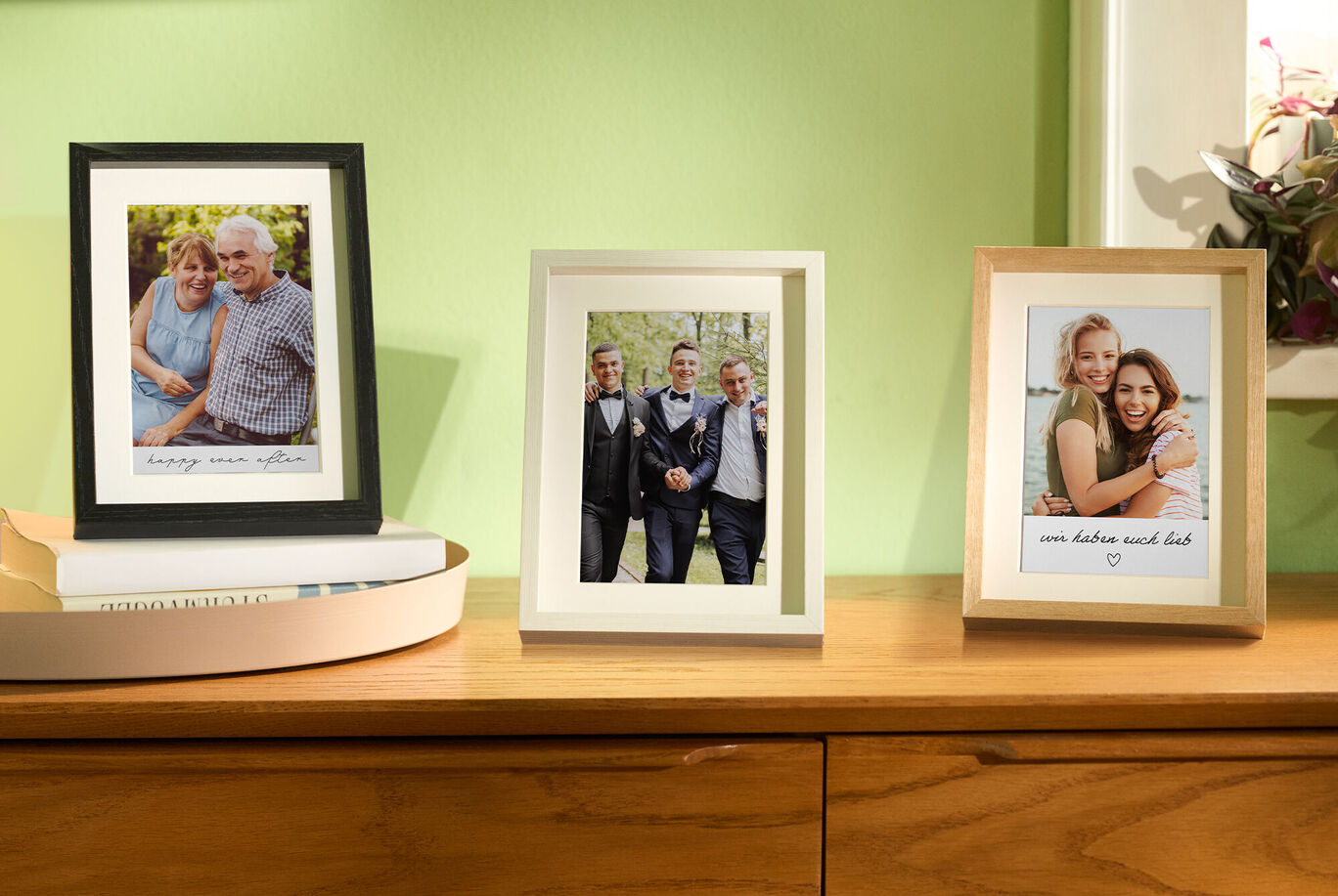 Drei Bilderrahmen mit Fotos von Freunden auf einem Tisch