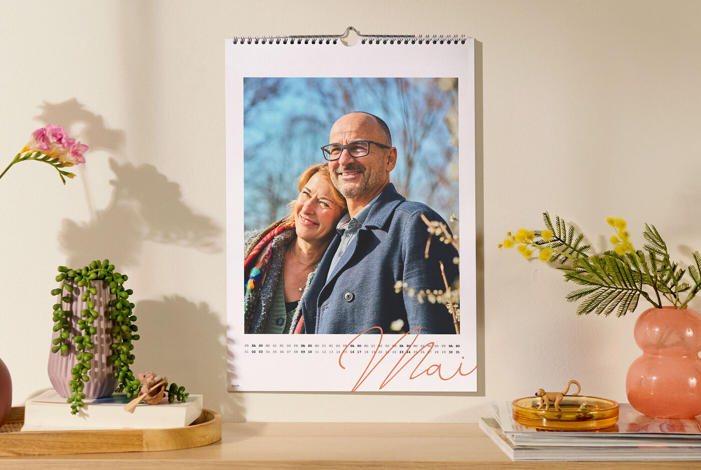 CEWE Fotokalender hängt an der Wand und zeigt ein persönliches Foto mit handgeschriebenem Monatsnamen.