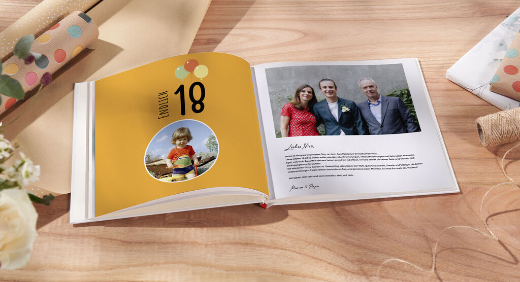 Ein CEWE FOTOBUCH mit bunten Ballons auf dem Cover und Fotos von einem feierlichen Anlass.